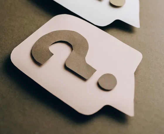 Paper question mark speech bubbles on a desk